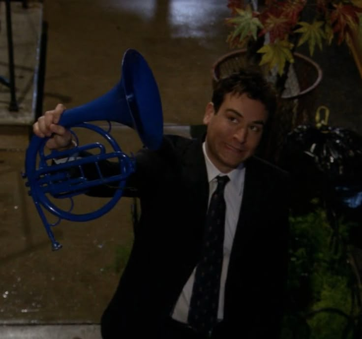 a man in a suit and tie holding a blue french horn