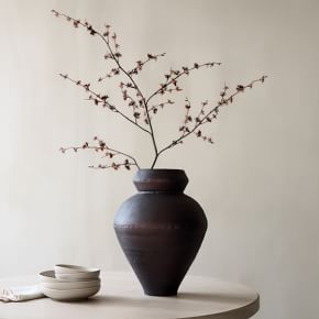 a vase sitting on top of a table next to a plate and bowl with flowers in it