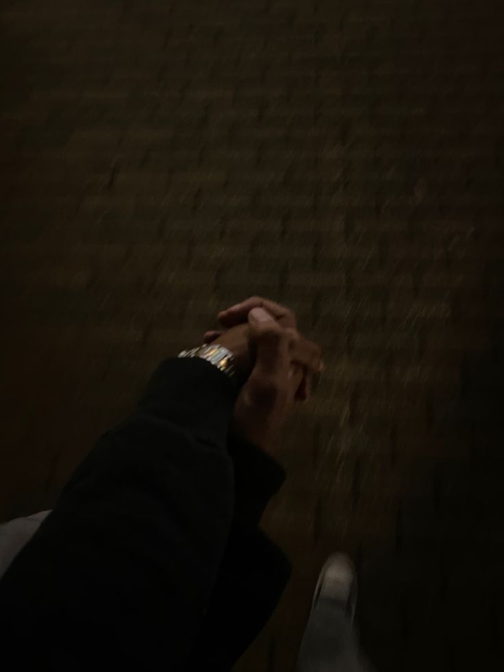 two people holding hands in front of a wall with words written on it and one person's hand reaching up to the ground