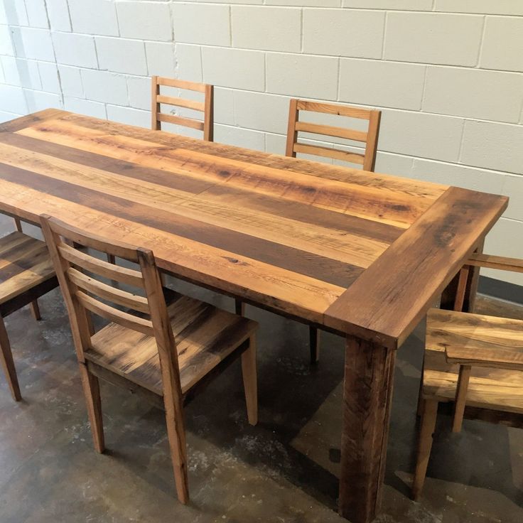 a wooden table with chairs around it in front of a white brick wall and floor