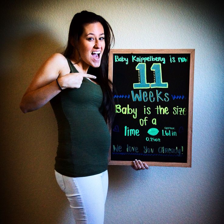 a woman in white pants and green tank top holding up a chalk board