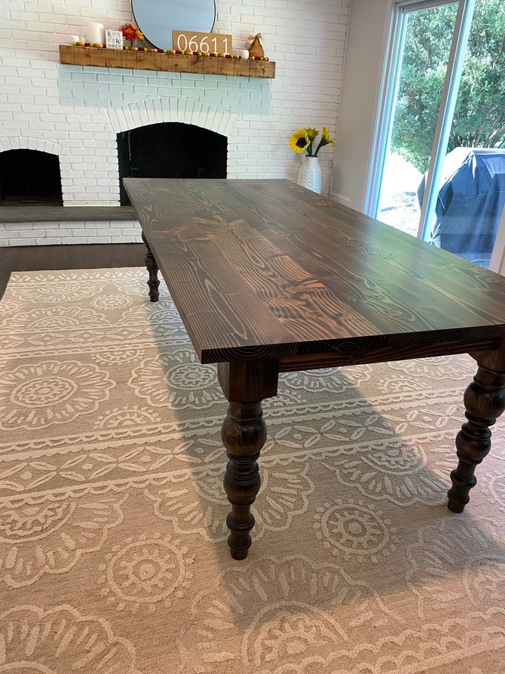 a large wooden table sitting on top of a carpeted floor next to a window