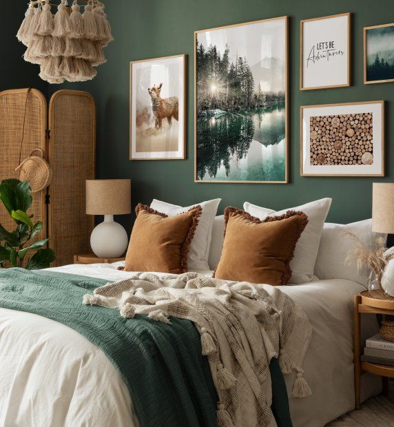 a bedroom with green walls and pictures on the wall above the bed, along with two lamps