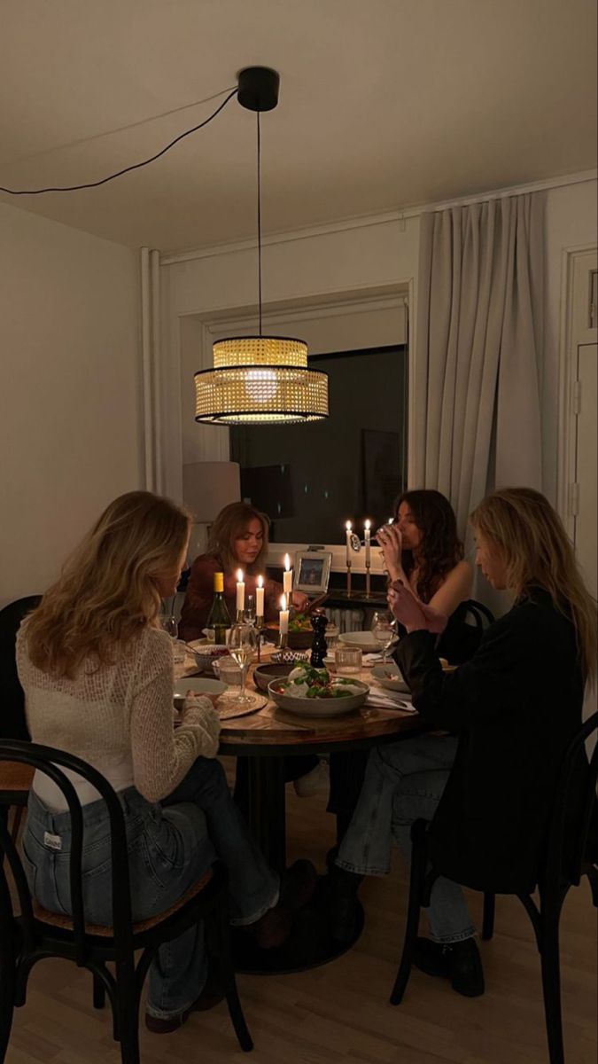 a group of people sitting around a table with food and candles in front of them