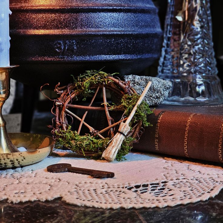 a candle and some branches on a table next to an old book with a lace doily