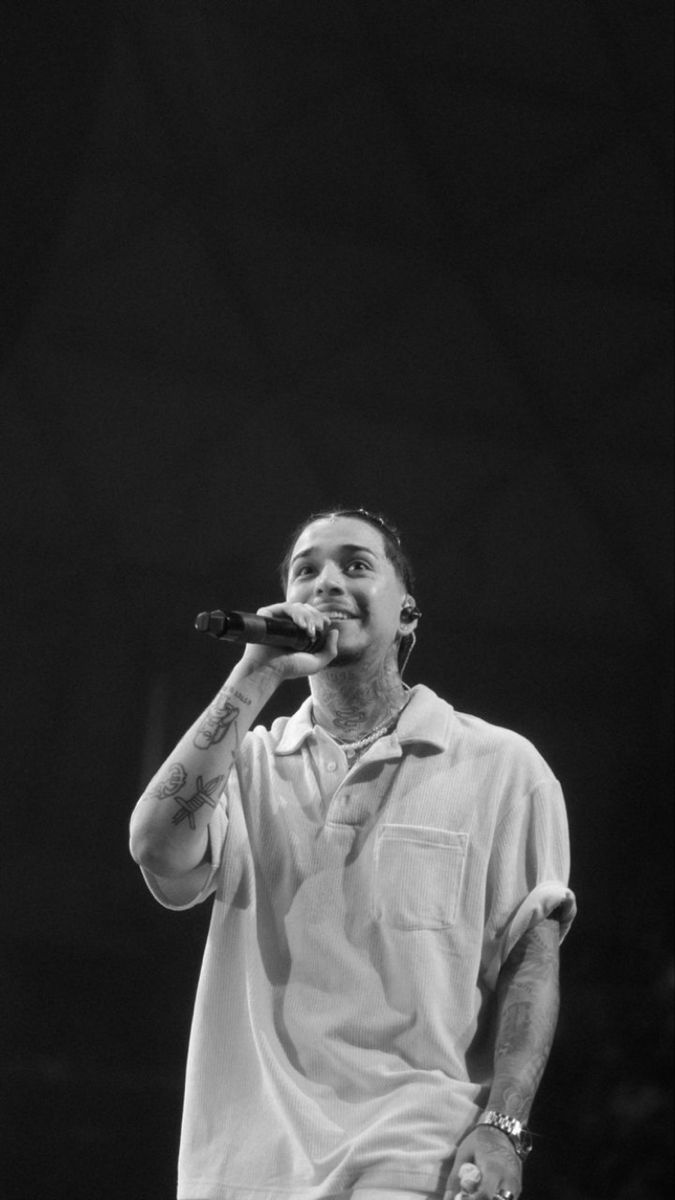 a black and white photo of a man holding a microphone in his right hand while standing on stage