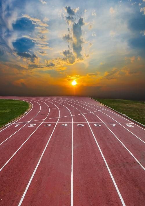 the sun is setting over a running track