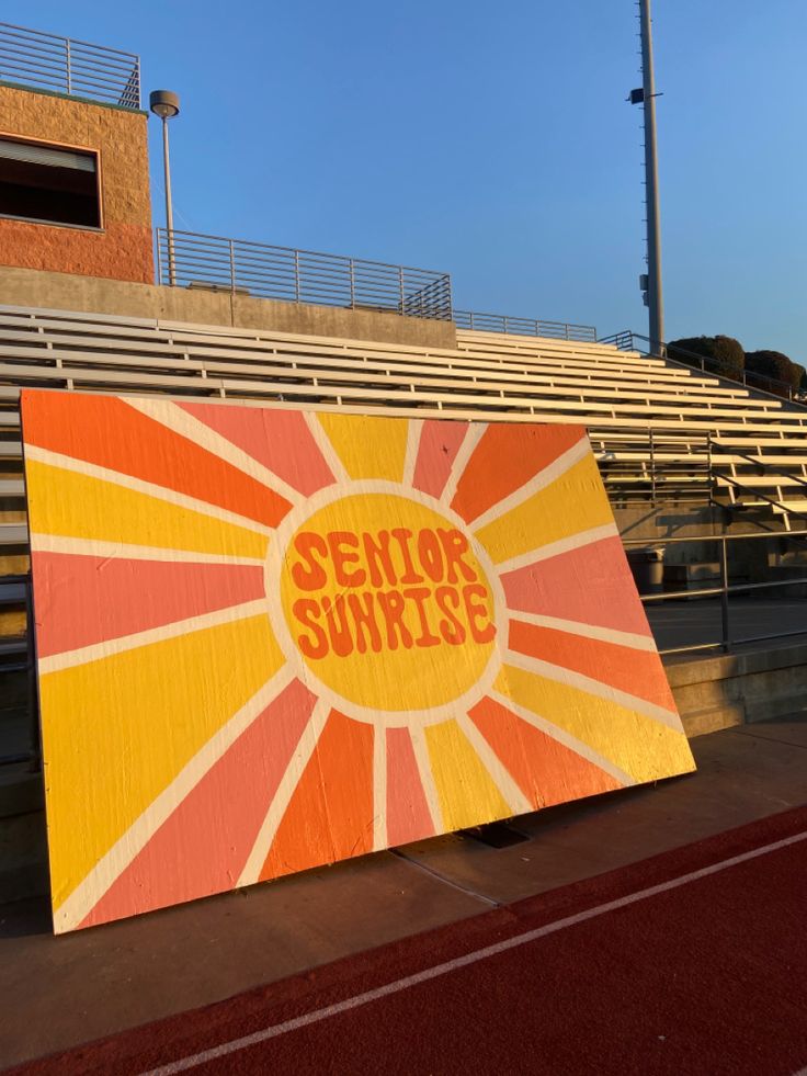 an orange and yellow sign that says senior sunrise on it in front of some bleachers