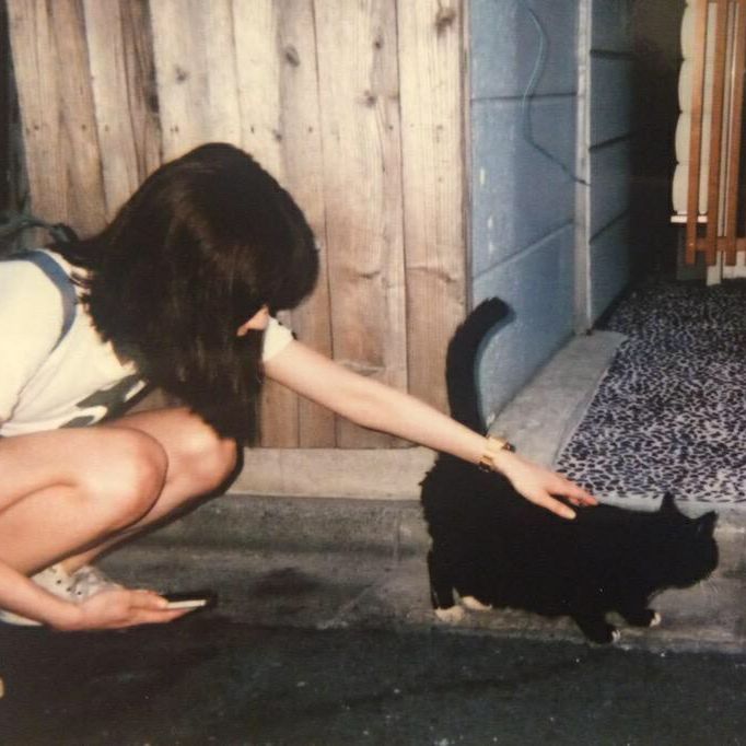 a woman kneeling down petting a black cat