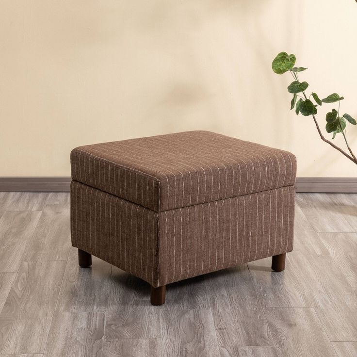 a brown ottoman sitting on top of a wooden floor next to a potted plant