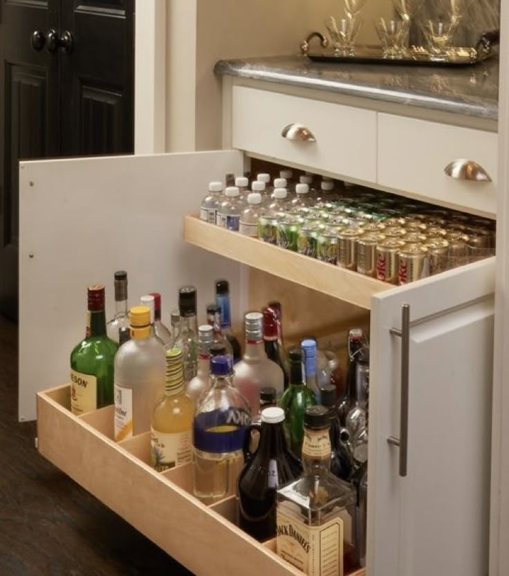 an open cabinet filled with liquor bottles and glasses on top of a wooden floor next to a counter