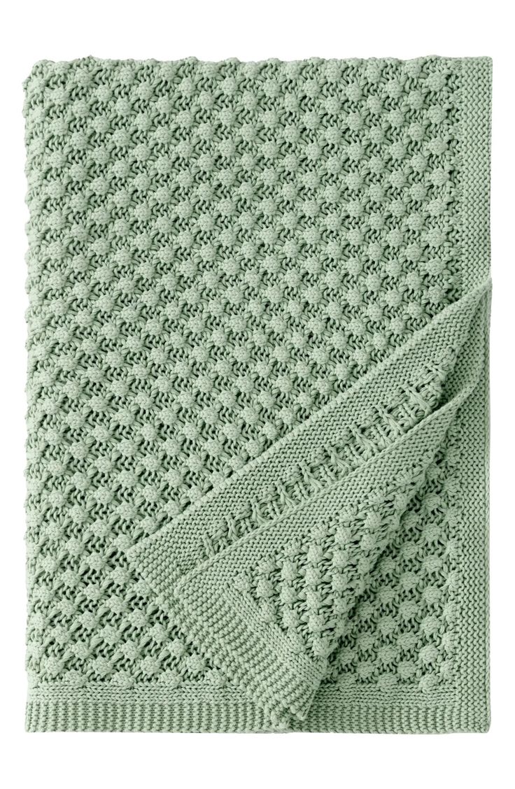 a green knitted blanket on top of a white background