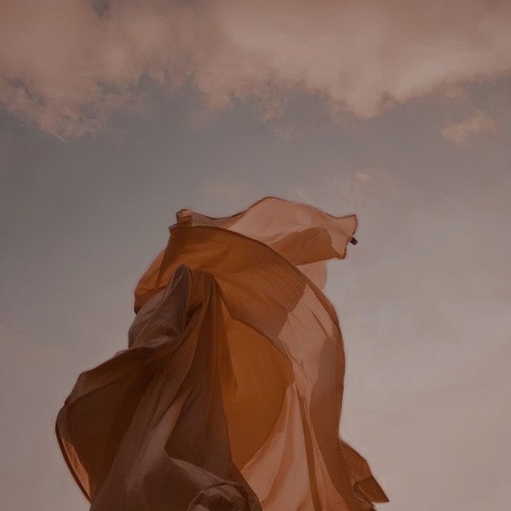 a woman is flying a kite in the sky with her hair blowing back into the wind