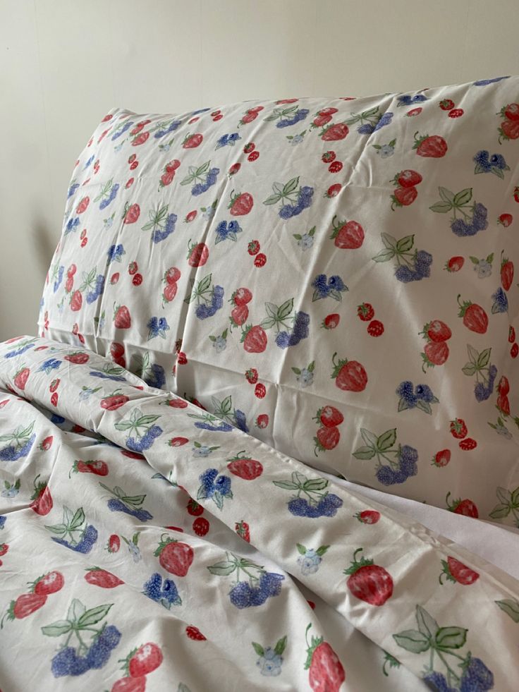 an unmade bed with cherry print on it