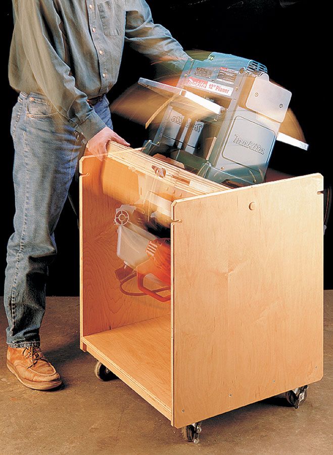 a man standing next to a wooden cabinet filled with assorted items on wheels,