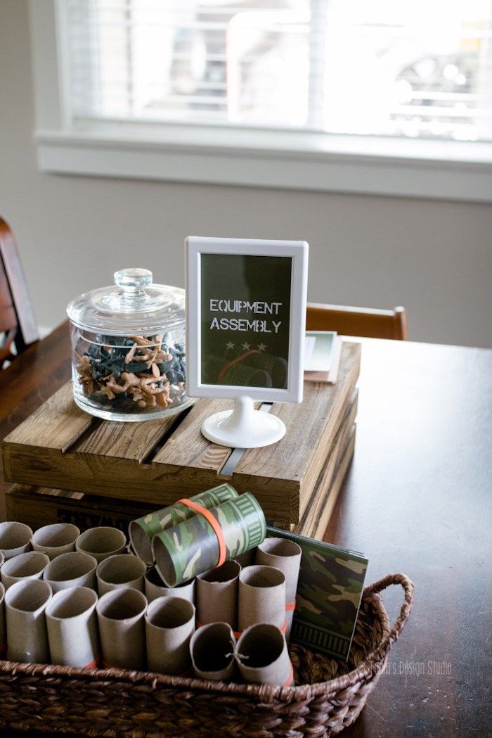 a wooden table topped with lots of cups next to a basket filled with books and magazines