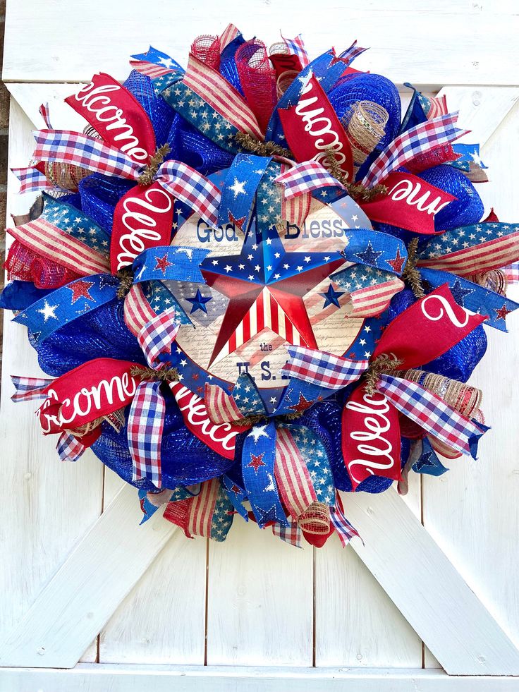 a patriotic wreath on a white door with red, white and blue ribbons around it