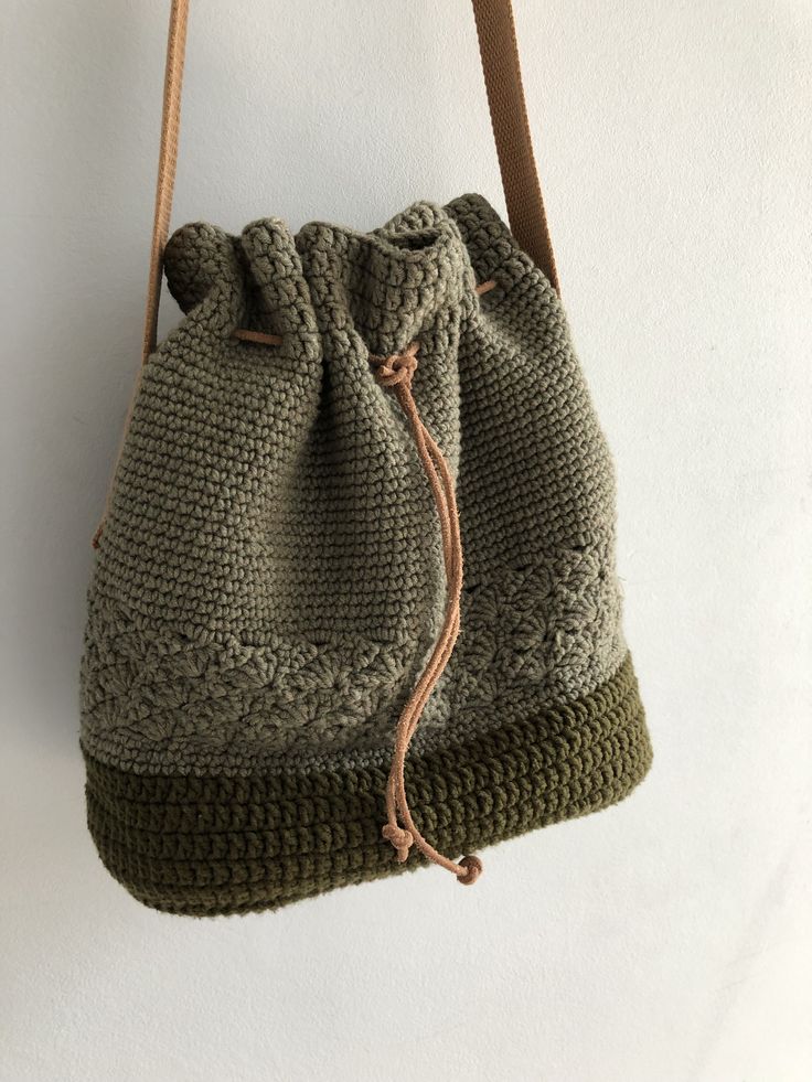 a crocheted drawstring bag hanging from a hook on a white wall