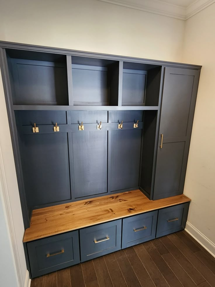 a large wooden bench in the middle of a room with blue cabinets on both sides