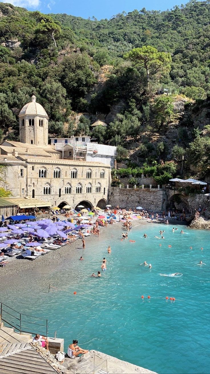 people are swimming in the blue water near an old building