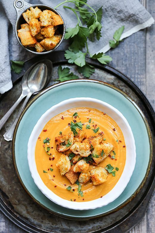 a bowl of soup with croutons and garnishes on the side