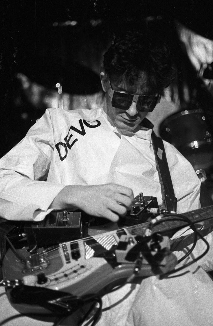 black and white photograph of a man playing an electric guitar with the words devc on it