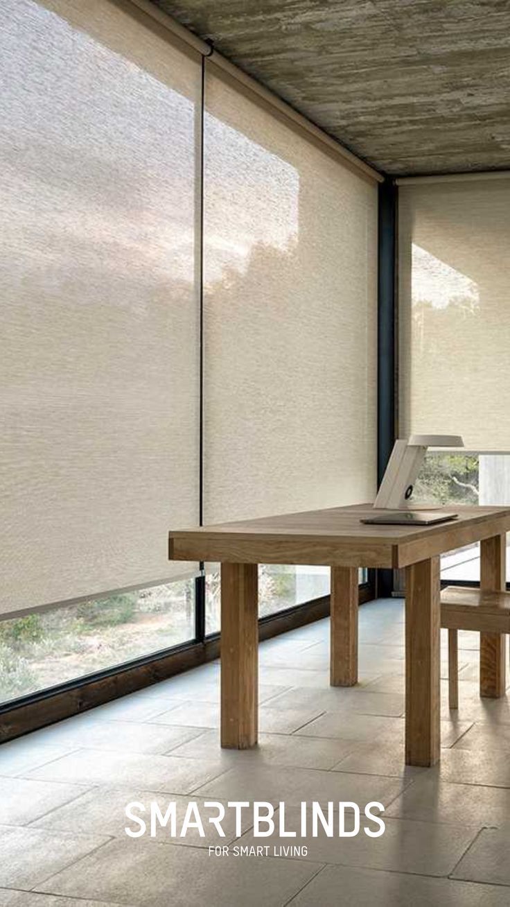 a table and two chairs in front of windows with blinds on the window sill