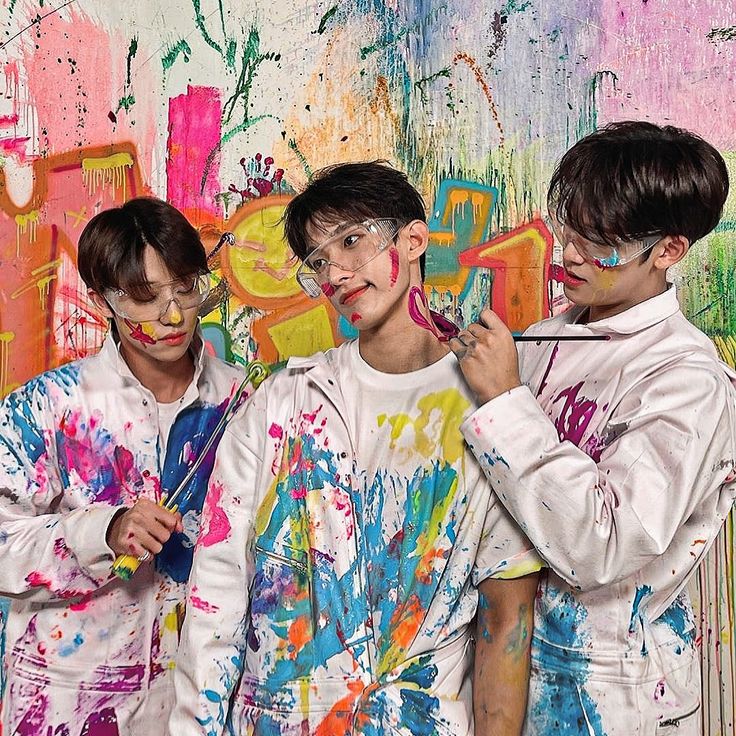 three boys with paint on their faces and body are standing in front of a colorful wall