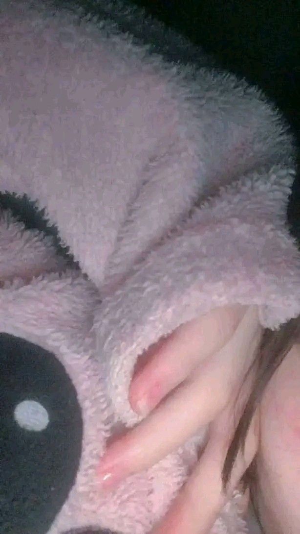 a woman laying on top of a pink teddy bear with her hand under her chin