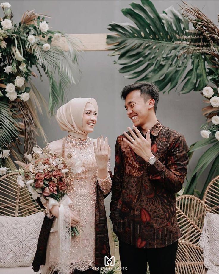 a man and woman standing next to each other in front of some palm trees with white flowers