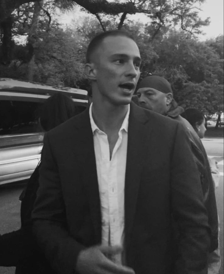 a black and white photo of a man in a suit talking to someone on the phone