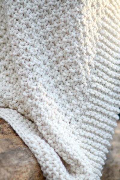 a white knitted blanket sitting on top of a wooden table