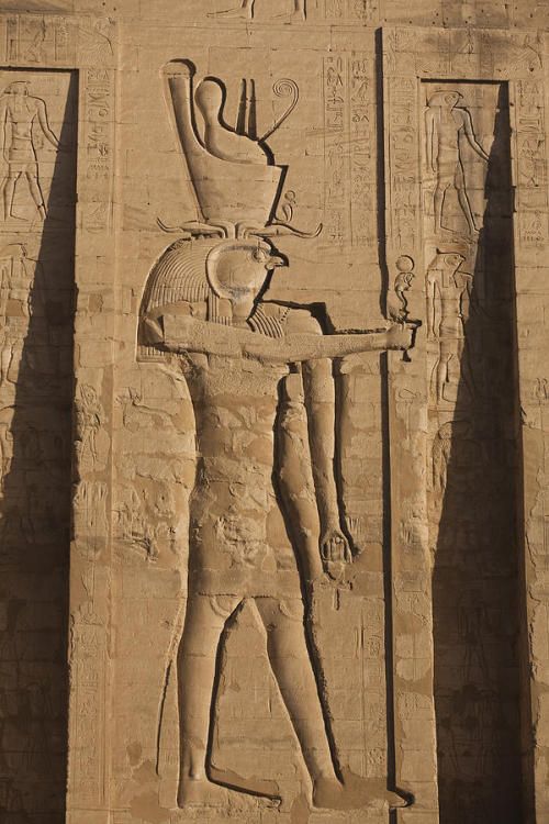 an ancient egyptian carving on the side of a building with a man holding a bowl