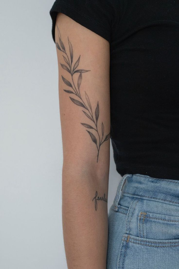 a woman's arm with a tattoo on it and a branch in the middle