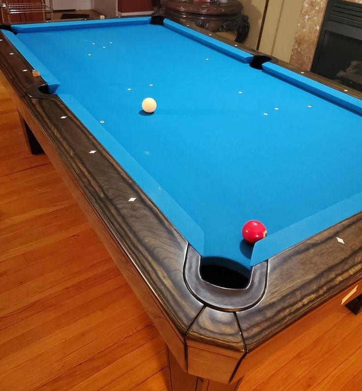 a blue pool table sitting on top of a hard wood floor