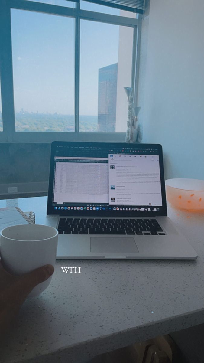 a laptop computer sitting on top of a white counter next to a cup and bowl