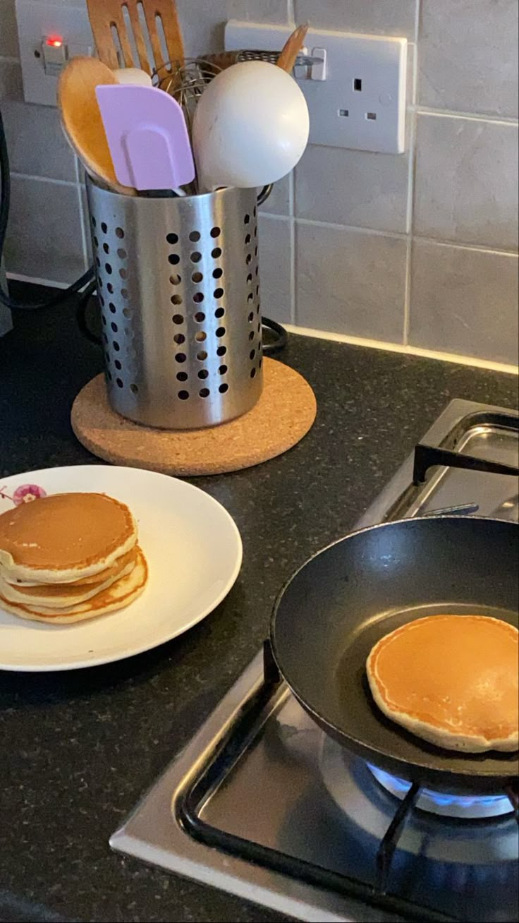 pancakes and utensils are sitting on the stove top, next to a pan