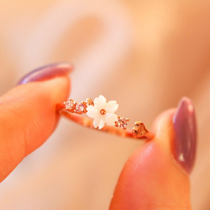 Description: Feel your style flower with our dainty White Flower Ring! Crafted with mother of pearl flower and dainty pink gems, it's sure to bring a twinkle to any outfit. Blooming gorgeous! Ring Details: Material: 18K Rose Gold Vermeil / 18K Gold Vermeil / Sterling silver Anti-allergy and nickel-free. Size: 4-8 Adjustable. Designed in LA In order to extend the life of your jewelry, please remove jewelry before swimming, exercising & bathing. White Flower Ring, Gorgeous Ring, Pink Gem, Pearl Flower, Flower Ring, White Ring, White Flower, 18k Rose Gold, Rose Gold Ring