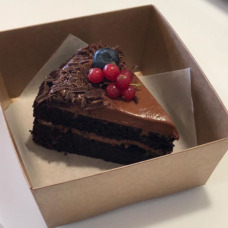 a piece of chocolate cake in a box with cherries on top and one slice missing