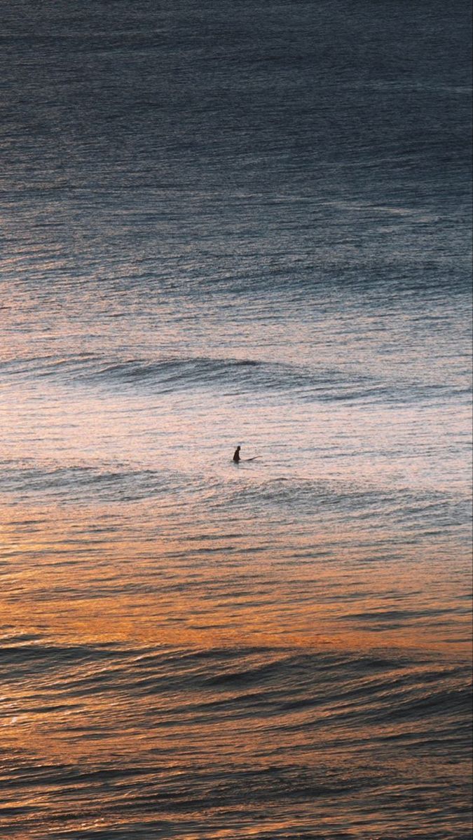 a person riding a wave on top of a surfboard in the ocean at sunset