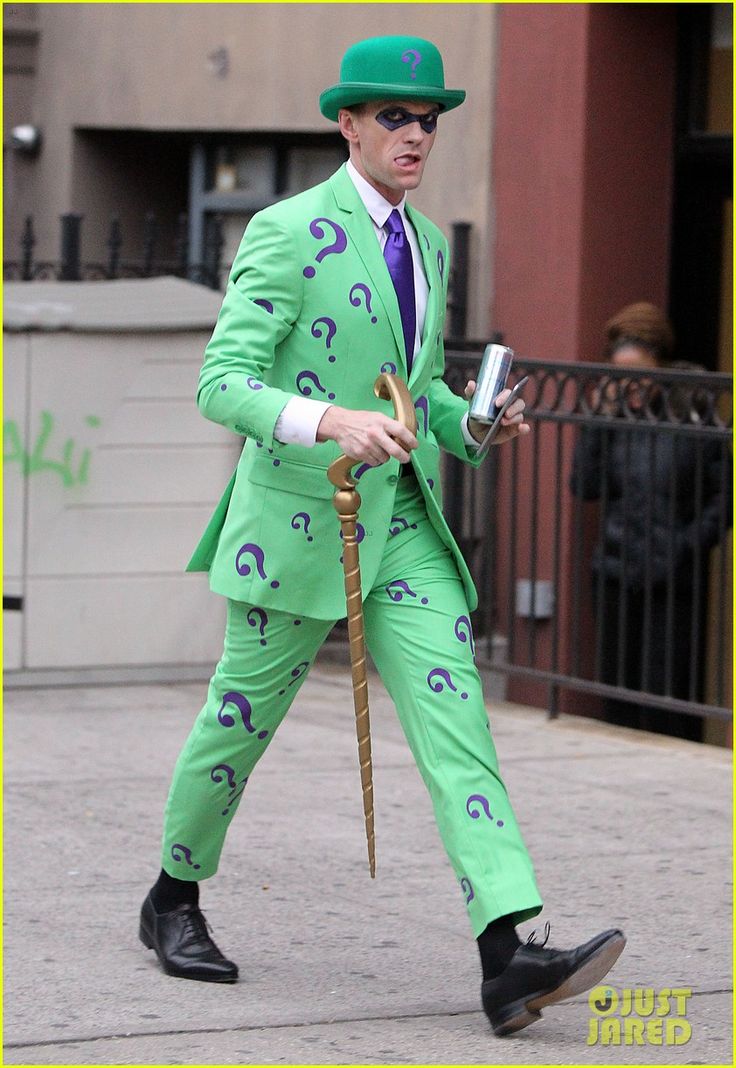 a man in a green suit and hat walking down the street