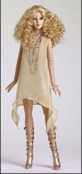 a doll with blonde hair and gold shoes is standing on a white background wearing a dress