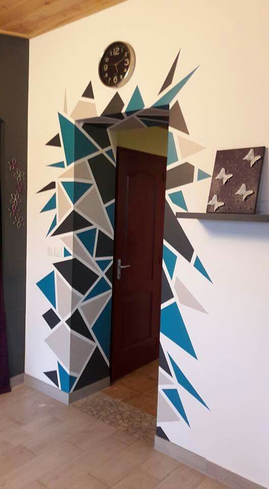 a clock is on the wall next to a door with an artistic design painted on it