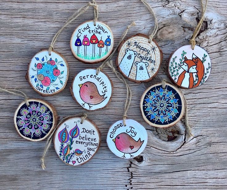 six hand painted ornaments hanging from string on wooden surface