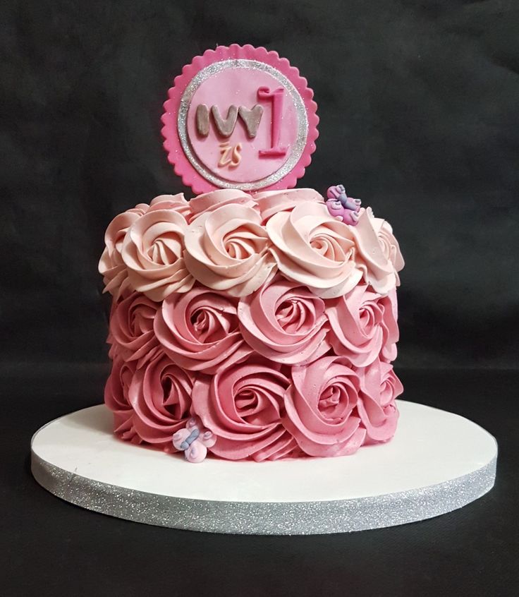 a pink and white cake with roses on the top is decorated with an i love you sign