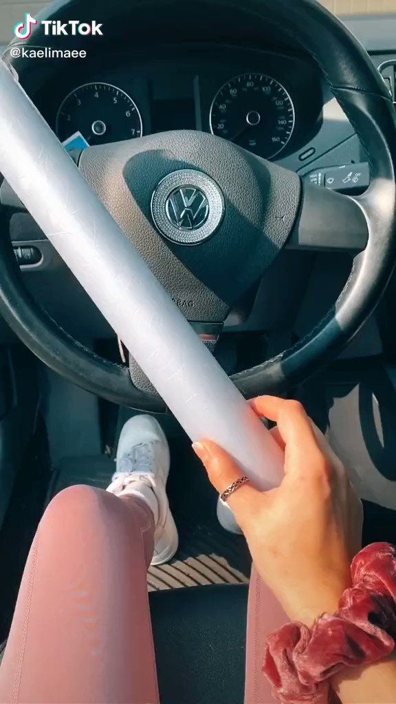 a woman is sitting in the driver's seat of a car with her hand on the steering wheel