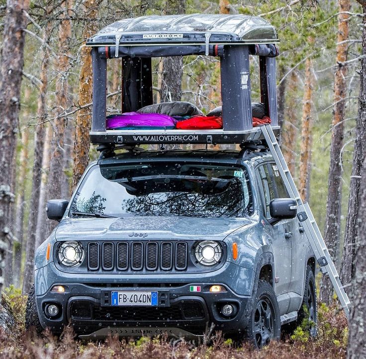 the jeep is parked in the woods with its roof rack on it's back