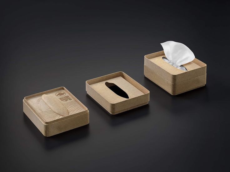 three wooden boxes with tissue and napkins in them on a black surface, one is empty