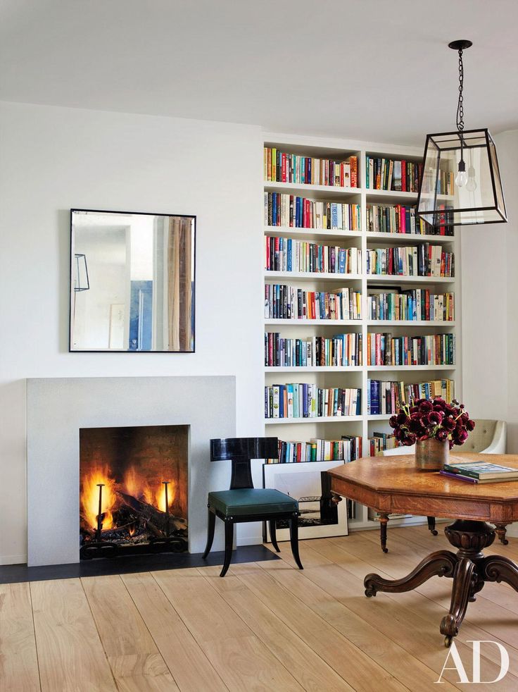 a living room filled with furniture and a fire place in front of a book shelf