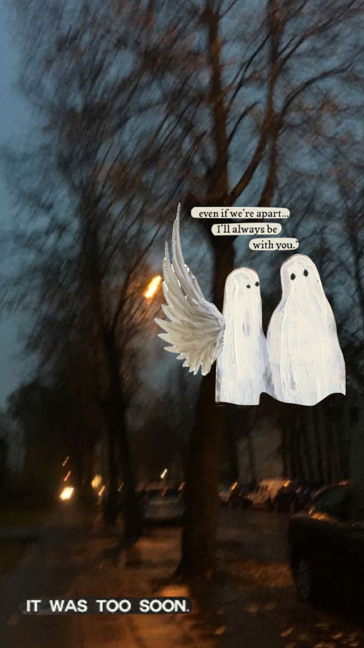 there are two white ghost statues on the side of the street with words above them